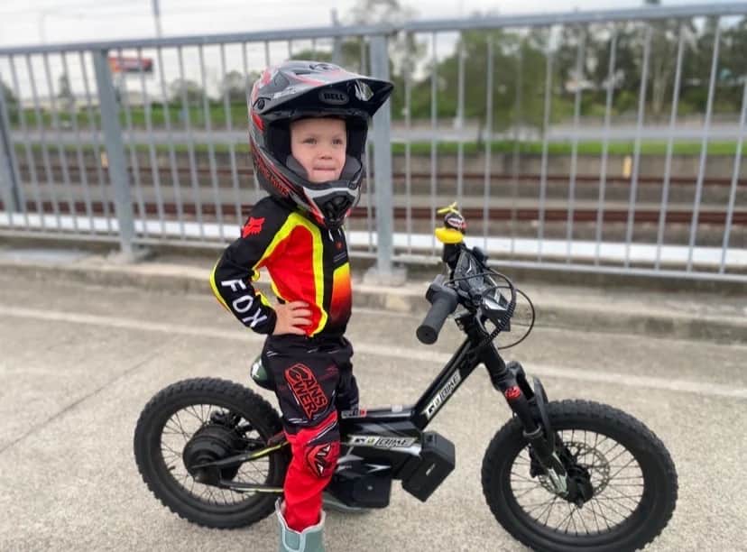 Young rider in full motocross gear standing beside his GoBike 16