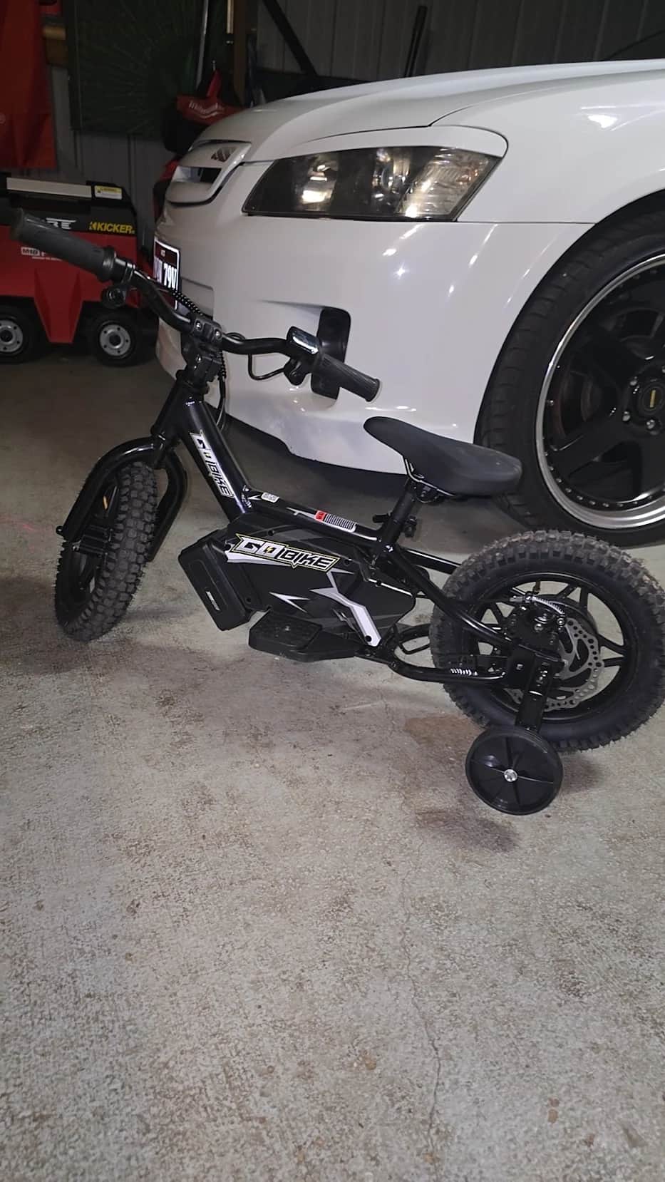 GoBike 12 electric balance bike with training wheels parked in a customer’s garage