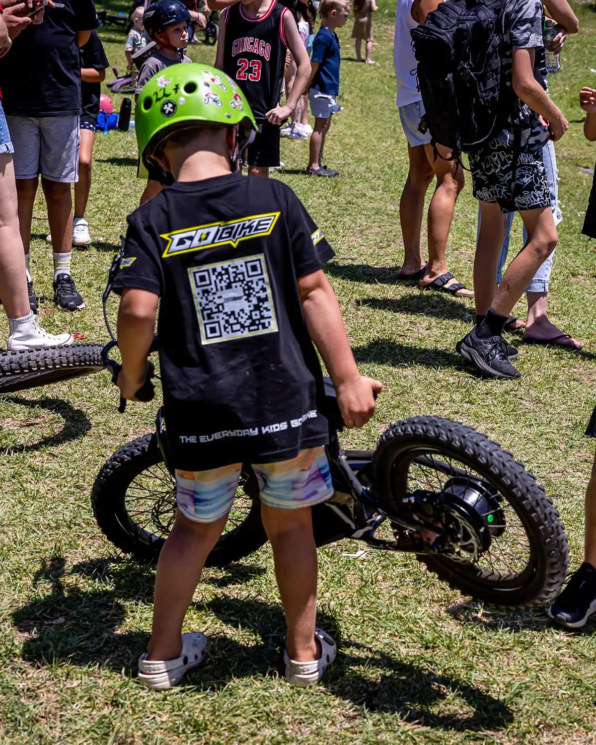 Young rider in a GoBike "The Everyday Kids eBike" T-shirt picking up his kids electric bike
