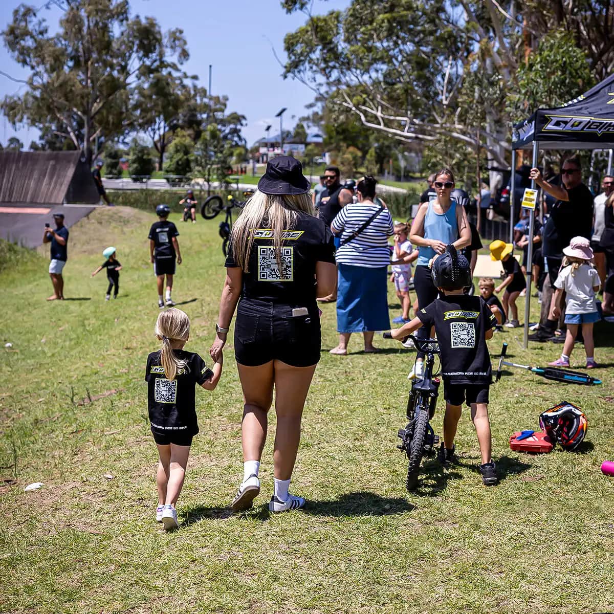 Mum and daughter walking hand in hand in matching GoBike kids T-shirts at a ride day