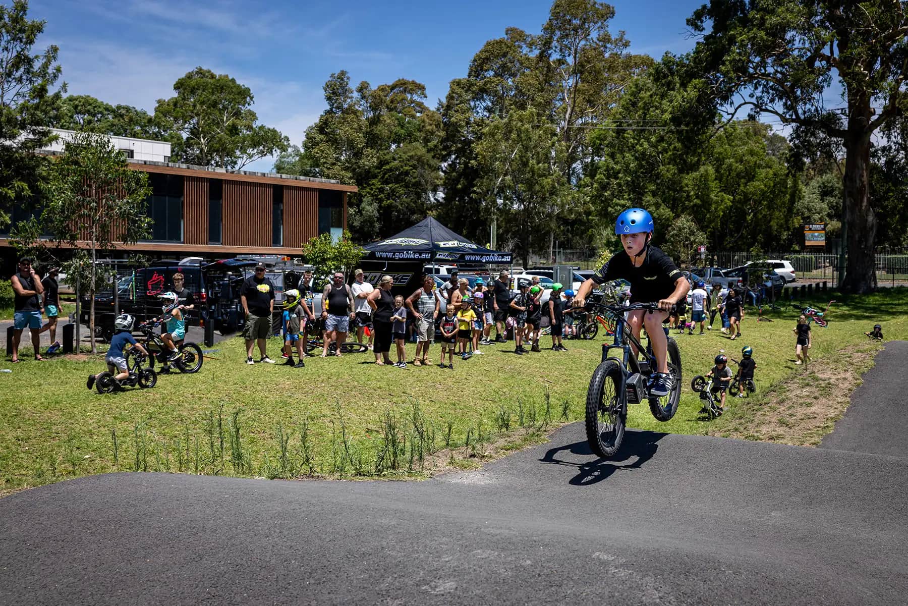 Teen rider lifting the front wheel of his GoBike 20 on the pump track at a ride day