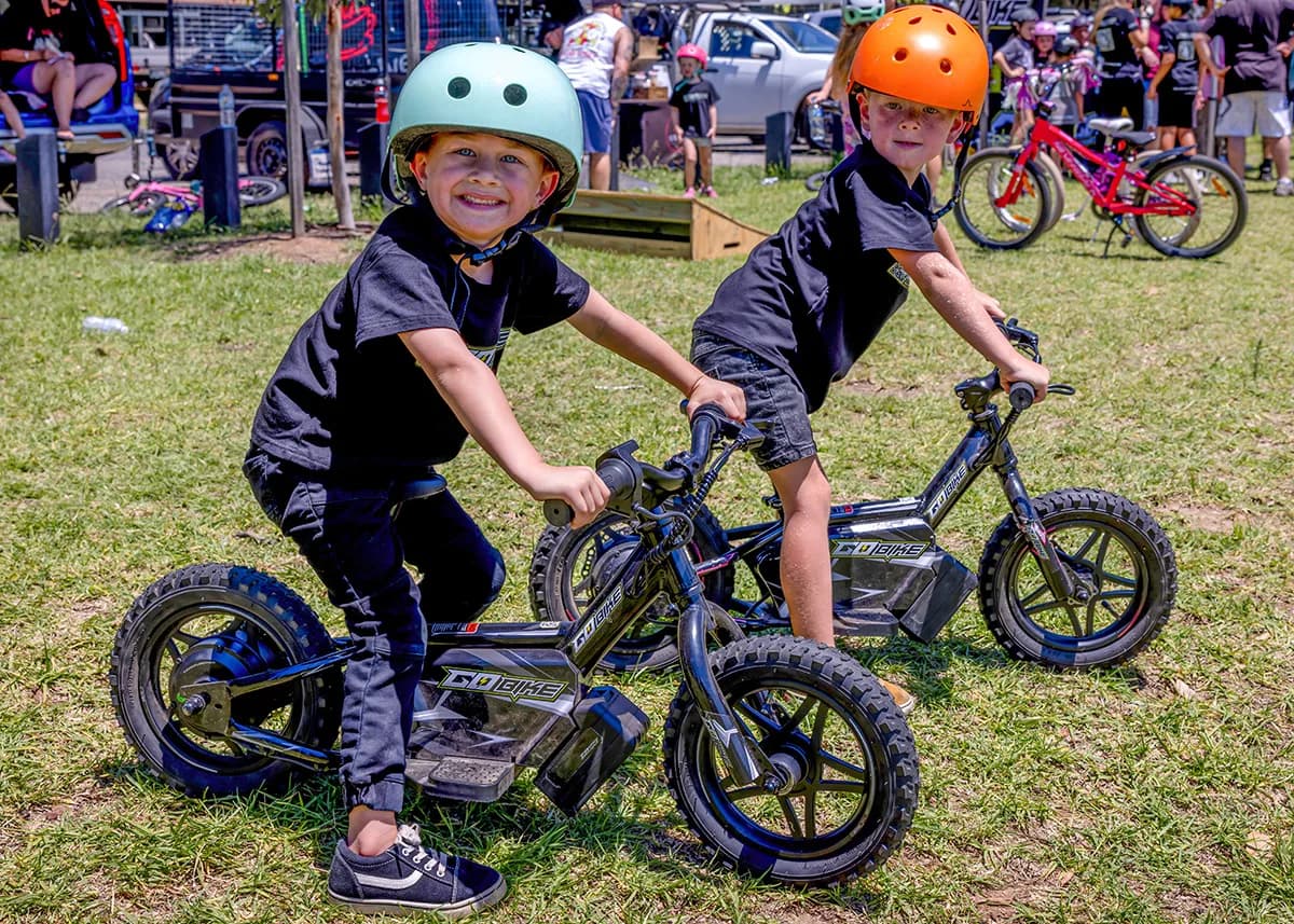 A happy young child confidently riding the GoBike 12 on a paved path.