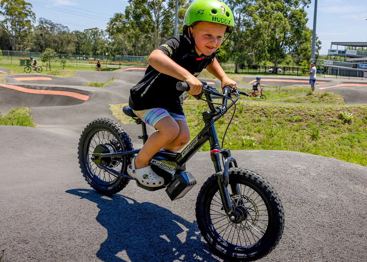 A young boy confidently riding the Gobike 16 electric bike on a pump track.