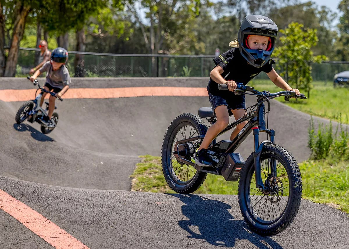 A young rider leans into a turn on a pump track with the GoBike 20 e-bike.