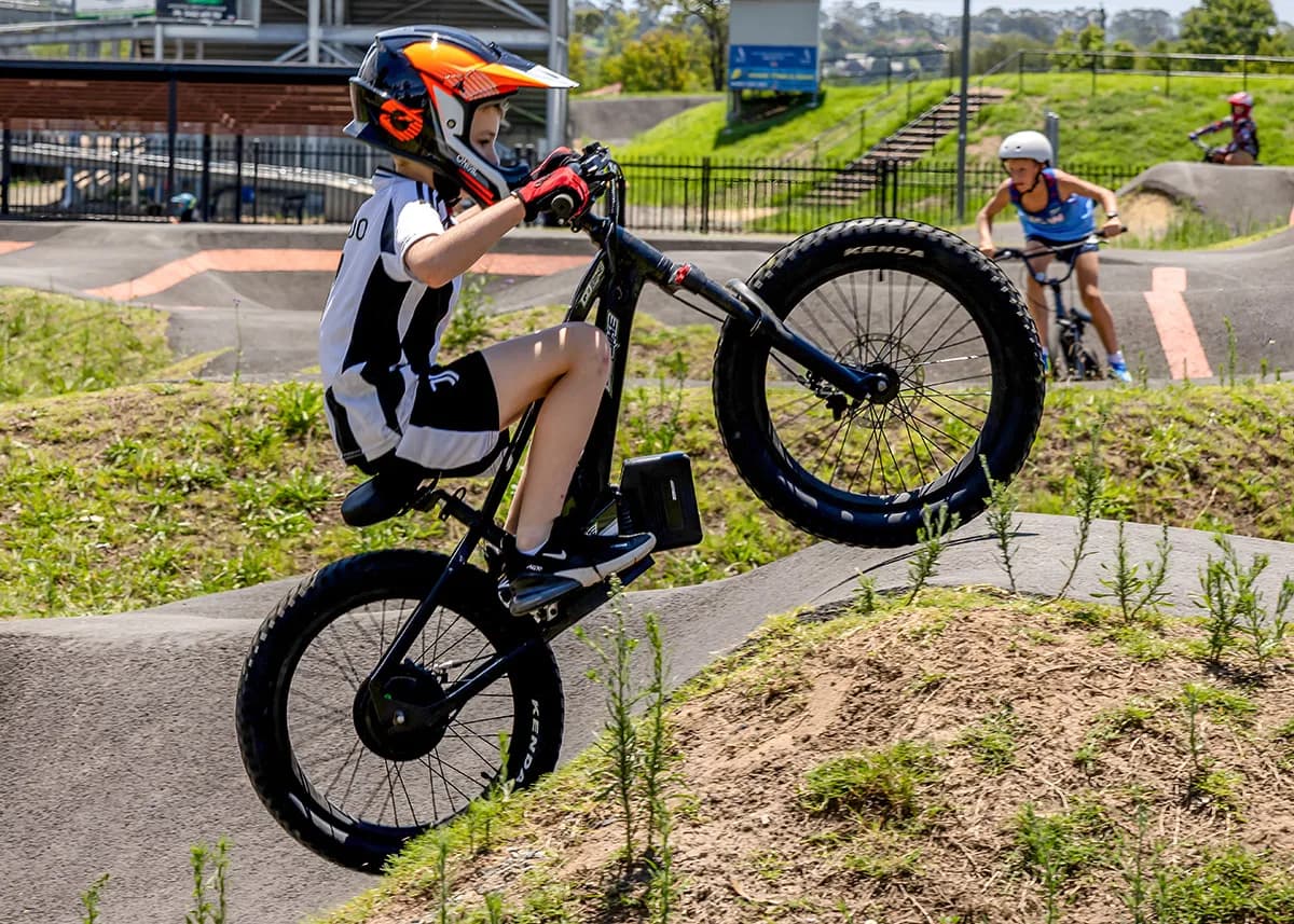 A young rider leans into a turn on a pump track with the GoBike 20 e-bike.