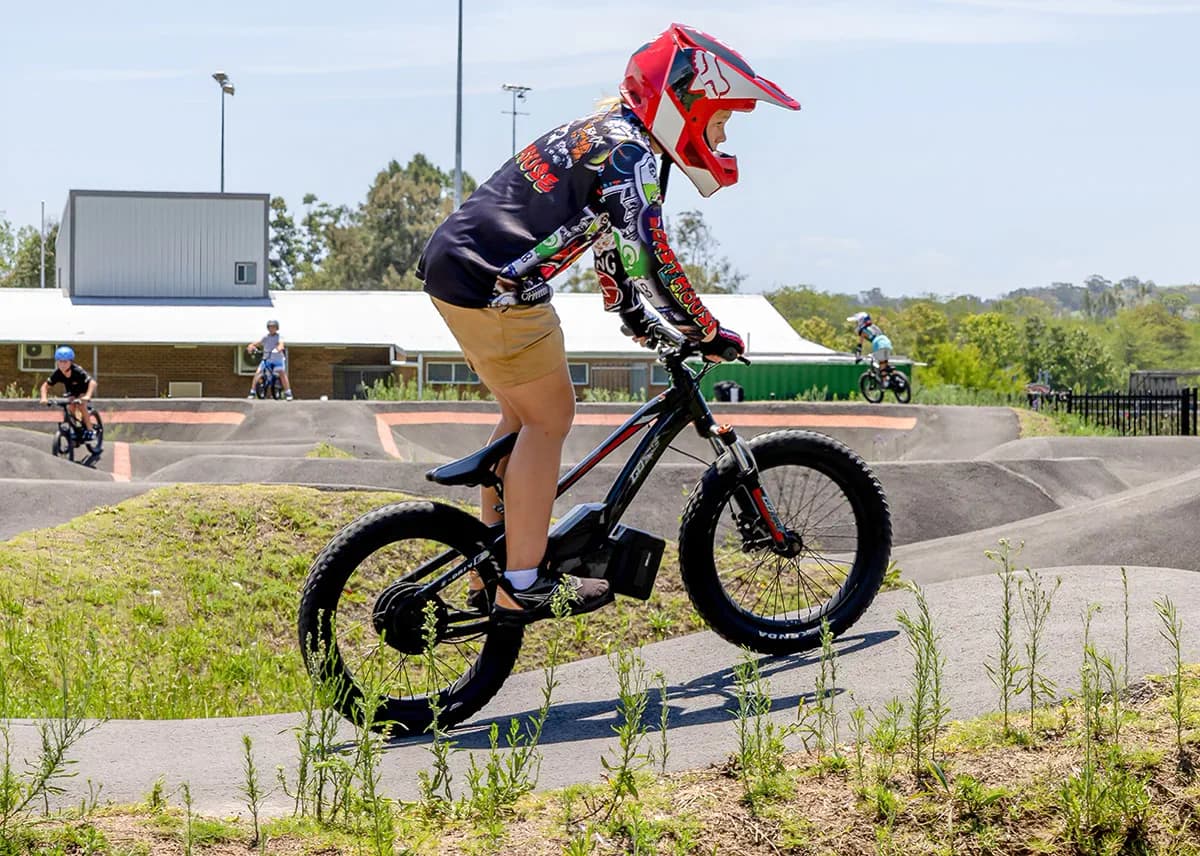 Young rider in a red full-face helmet on a GoBike 20 at a pump track