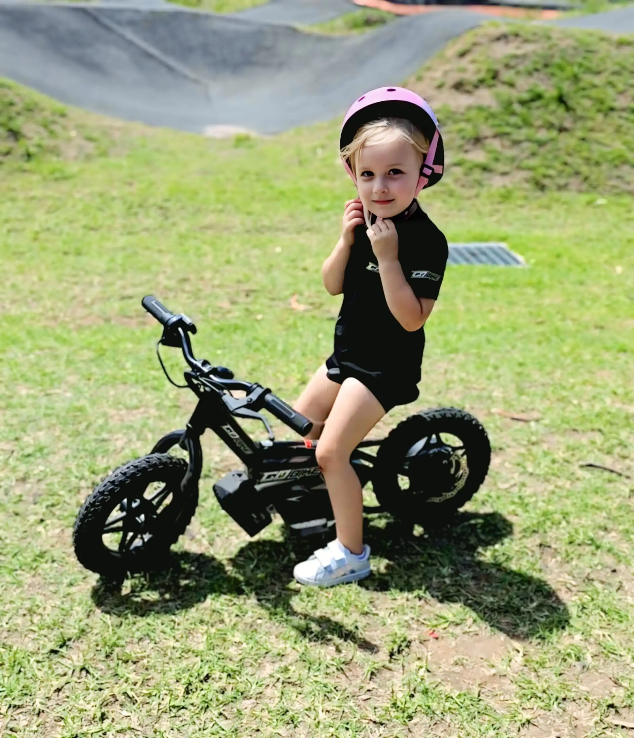 Little girl in a pink helmet on her GoBike 12 with her feet on the ground