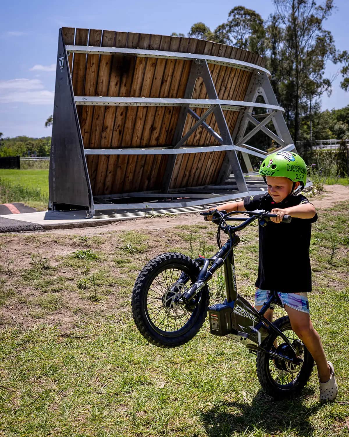 Young boy in a green helmet lifting the front wheel of his lightweight GoBike 12 kids e-bike