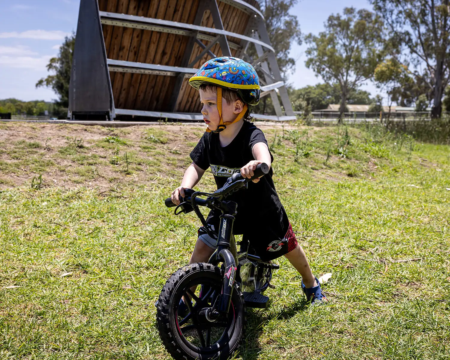 Toddler in a colourful helmet holding his GoBike 12, his first electric balance bike
